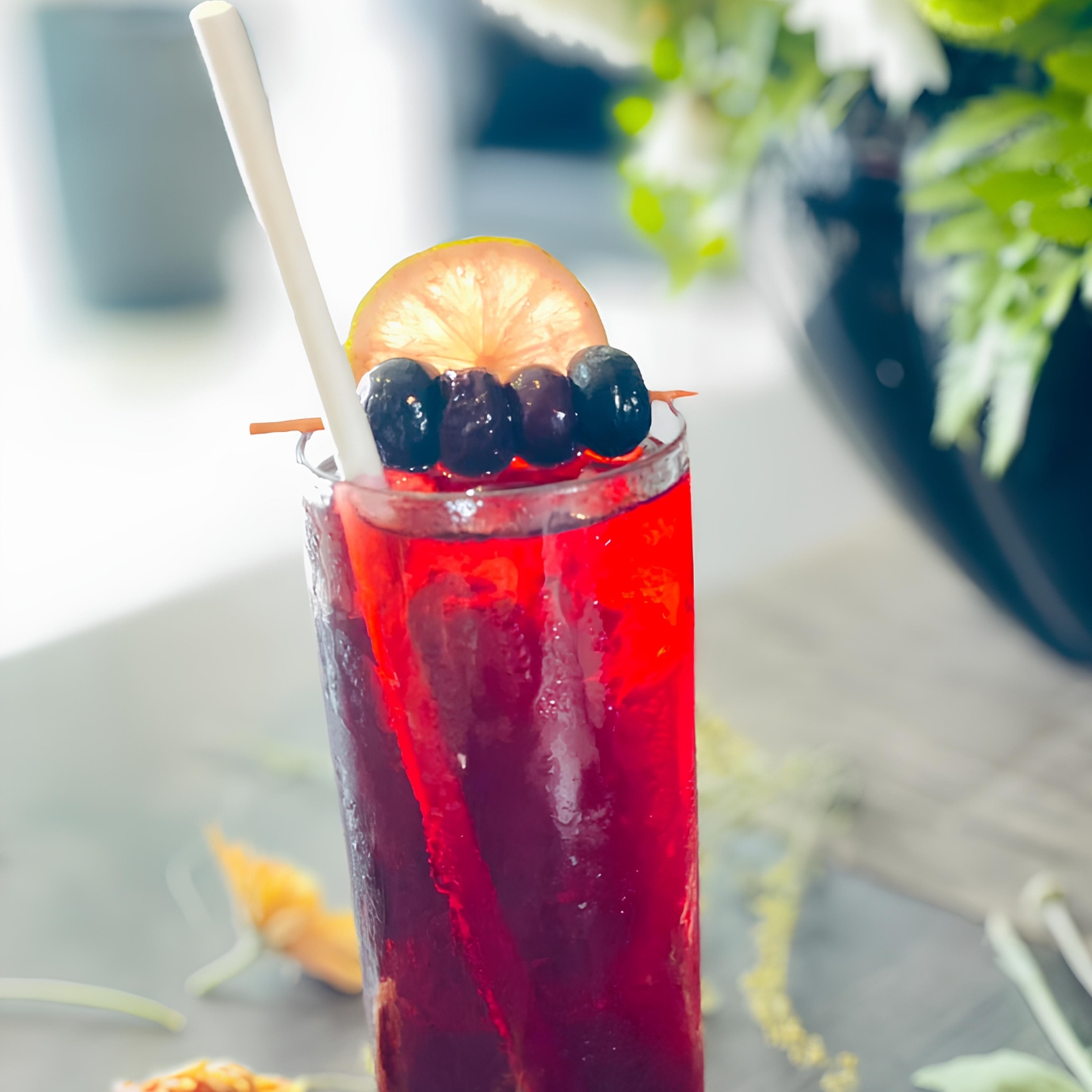 A tall glass of homemade blueberry iced tea, garnished with a lemon slice and fresh mint, sits on a rustic wooden table.