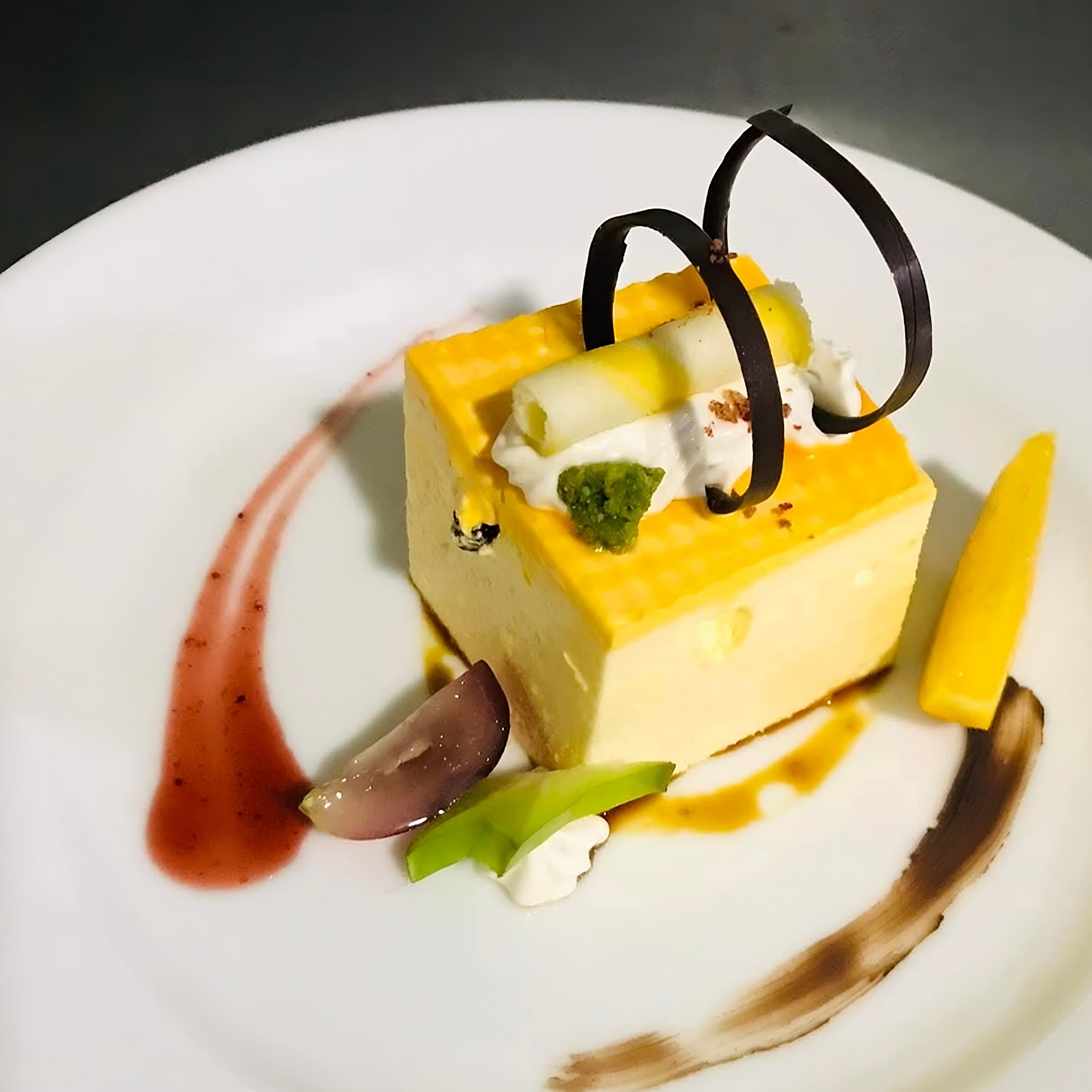 A sliced Zesty Orange and Ginger Cheesecake on a plate, showing its creamy filling, vibrant orange zest, and a crumbly ginger biscuit base.